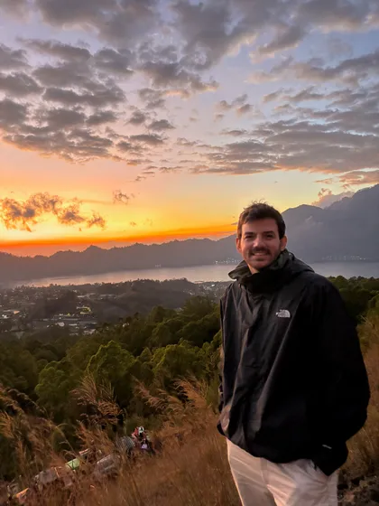 Timurcan on the hillside above Turkey's Mediterranean coast at sunset, mountains behind him and the sea below.